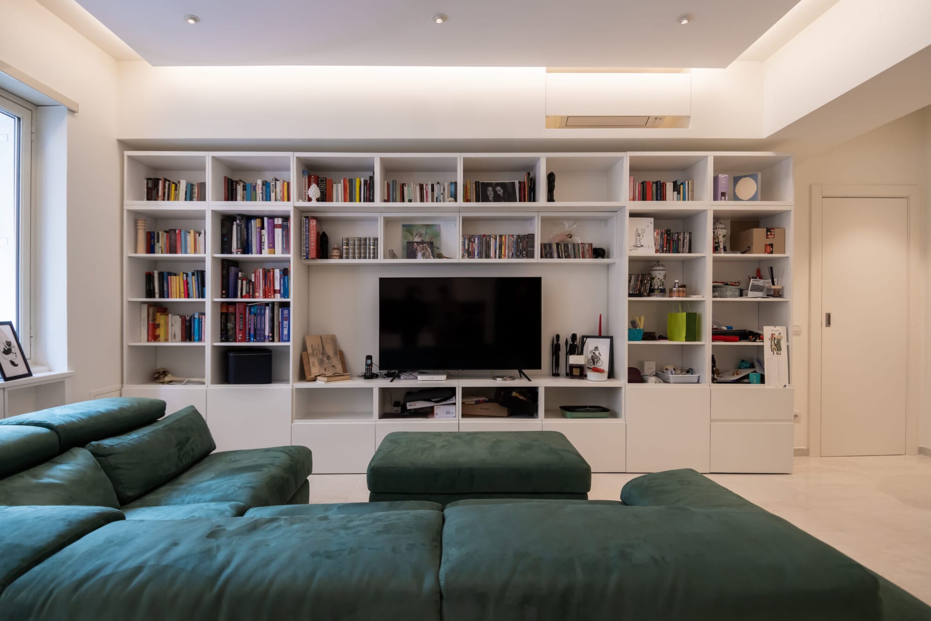 Soggiorno con libreria bianca e televisore a incasso, progetto Nomentano
